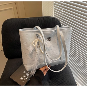 Close-up of light blue embossed tote bag with pearl lace bow charm and chic pattern
