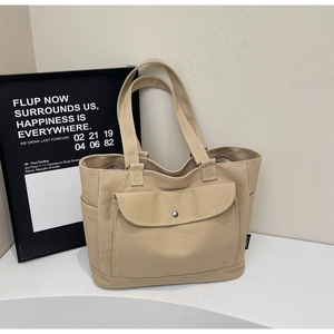 Detail of canvas tote bag showing side pocket and front metal buckle in beige color