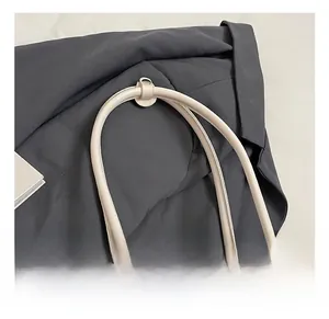 Detail of the stitched leather handle on a minimalist cream-colored Boston handbag