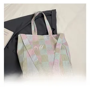 Detail of colorful plaid canvas tote bag with Meares cursive embroidery and dual strap design