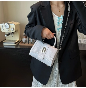Detail of white crocodile embossed mini bag with silver metal twist lock and chain strap