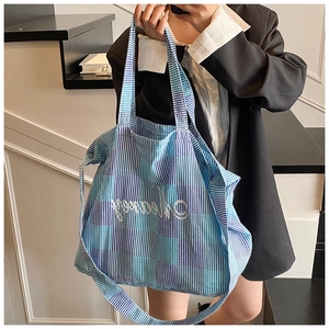Detail of blue and white checkered tote bag featuring a detachable wide shoulder strap