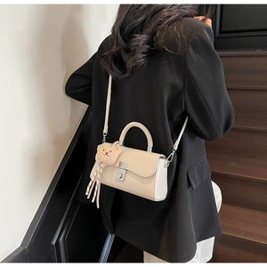 Detailed back view of a beige crossbody bag featuring a cute plush bear charm decoration