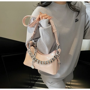 Pink glossy leather shoulder bag with thick silver chain worn by model on stairs