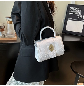 Close-up of white croc-embossed texture on handbags with silver metallic turn lock