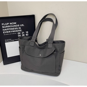 Detail view of large dark grey canvas tote bag with front flap pocket and side pockets