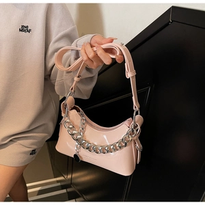 Detail of pink patent leather handbag with thick silver chain and adjustable strap