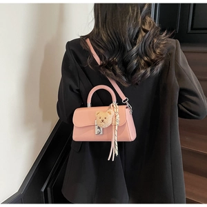 Detail of pink faux leather bucket bag featuring a metal lock and cute bear charm pendant