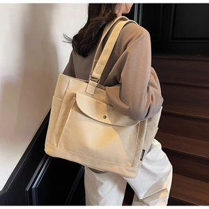 Detail shot of a beige canvas tote bag showing the side pocket and fabric texture