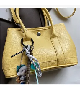 Detail der gelben Leder-Eimertasche mit Silberverschluss und süßem Hundeanhänger