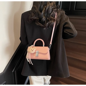 Pink matte PU leather handbag with bear charm and striped ribbon detail on stairs