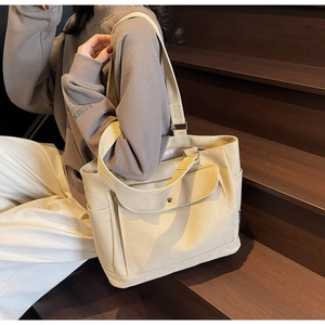 Detail showing beige canvas tote bag with multiple pockets and shoulder straps for commute