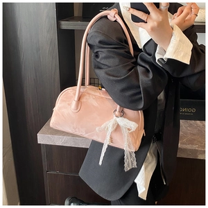 Pink glossy patent leather pillow bag with white lace bow and pearl detail close-up