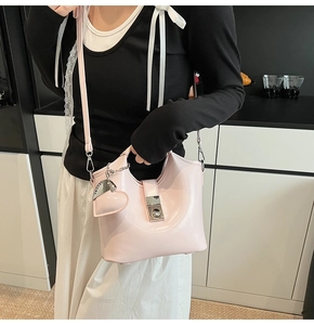 Detail view of pink patent leather bucket bag with silver heart charm and buckle