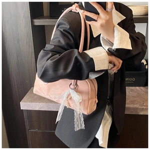Detail of pink glossy leather bag featuring white lace bow and pearl chain pendant