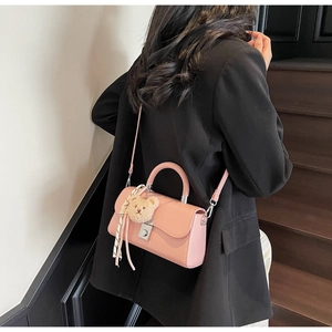 Close-up of pink glossy mini bucket bag with plush bear charm and silk scarf detail