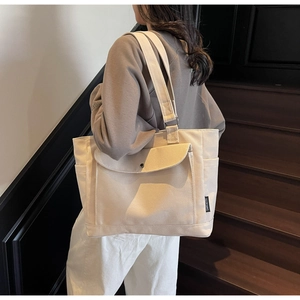 Canvas tote bag with front pocket and snap button shown on model in stairwell