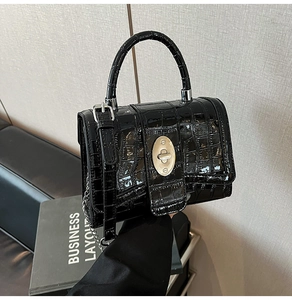 Close-up of black crocodile pattern leather handbag with silver oval twist lock