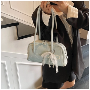 Close-up of light blue Boston bag with pearl lace bow charm in a modern minimalist setting