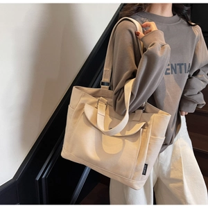 Detail of beige canvas tote bag showing side pocket, dual straps and durable fabric texture