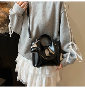 Detail view of black patent leather bucket bag with silver lock and heart charm