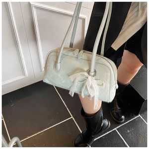 Detail of pale mint green patent leather shoulder bag with lace bow and pearl charm