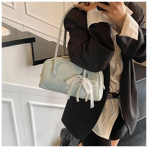 Detail of mint green glossy shoulder bag with lace bow and pearl chain accessories