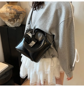 Detail of black patent leather handbag with silver heart charm and metal buckle lock
