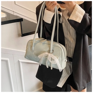 Detail of light blue patent leather bag with lace bow and pearl pendant on model