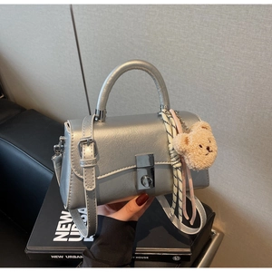 Detail of silver metallic bucket bag with ribbon scarf and plush bear charm ornament