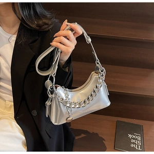 Macro detail of glossy silver shoulder bag with bold metallic chain and leather texture