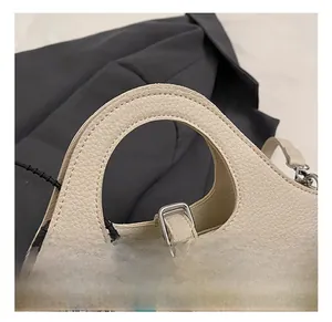 Detailed macro view of cream litchi texture leather handbag with circular handle and metal hardware