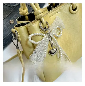 Détail du sac seau jaune avec nœud en perles et pendentif cœur en métal