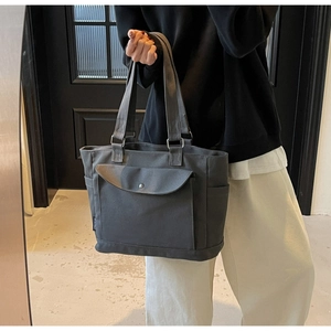 Detailed shot of dark grey canvas tote showing front flap pocket and metal snap button