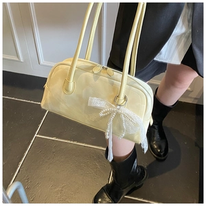 Detail of light yellow Boston bag with glossy leather texture and pearl lace bow charm