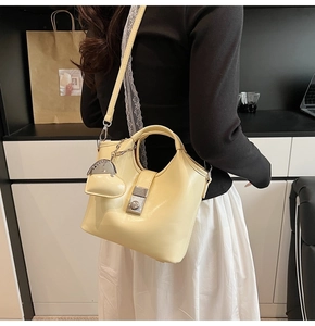 Close-up of cream yellow leather bucket bag with heart pendant and metallic clasp