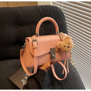 Detail of pink PU leather handbag with silver twist lock and plush bear charm