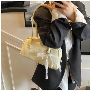 Detail of cream yellow Boston bag featuring lace bow and pearl charm for daily commute