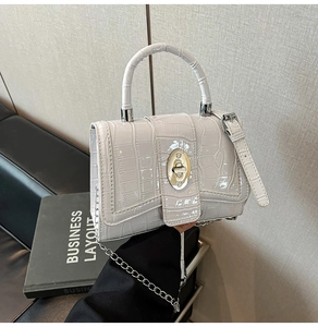 Detail of white crocodile texture handbag with gold metal twist lock and round handle