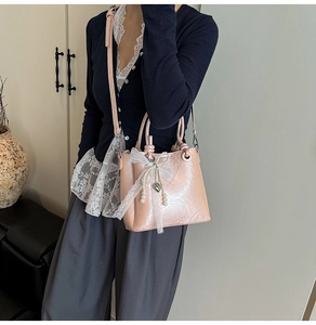 Détail du sac seau rose avec nœud en dentelle et pendentif perle sur un mannequin
