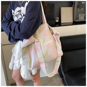 Close-up of colorful checkered tote bag with embroidered Mearey logo and shoulder strap