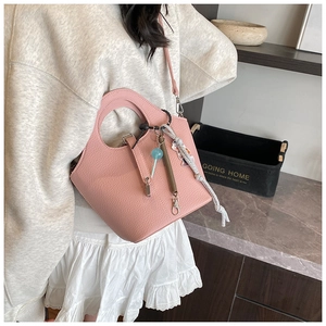 Pink lychee grain bucket bag with unique hollow handle and decorative charms
