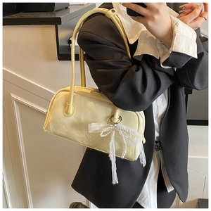 Detail of creamy yellow Boston bag featuring a decorative lace pearl bow charm