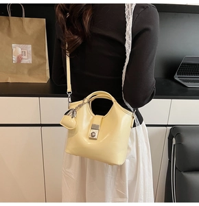 Detail of a cream bucket bag showing metal lock and heart charm on modern background