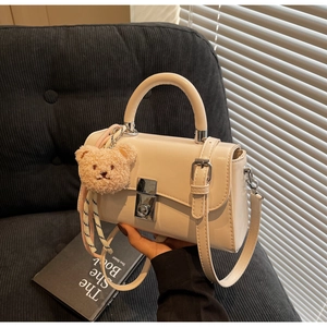 Detail of cream white leather mini bag with silver buckle and plush bear charm