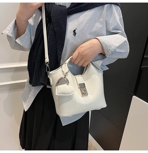 Detailed macro view of cream-colored bucket bag with silver buckle and heart charm