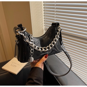 Detail of glossy black crescent shoulder bag with chunky silver chain and logo charm