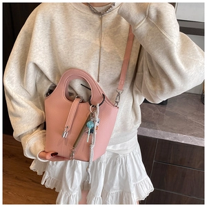 Detail of pink pebbled leather bucket bag featuring a metal lock and colorful charm
