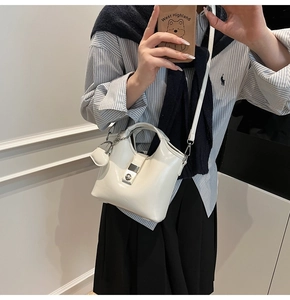 Close-up of creamy white glossy bucket bag with silver metal buckle and chain strap