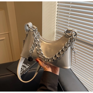 Detailed close-up of a silver crescent underarm bag featuring a chunky metal chain link